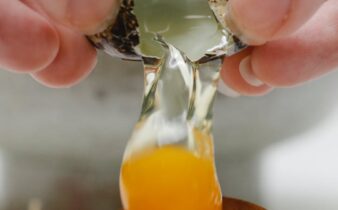person breaking quail egg while preparing breakfast