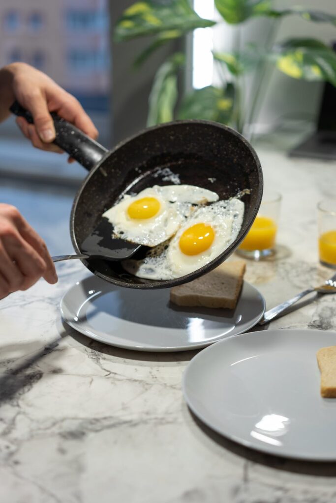 a person holding a pan with cooked eggs