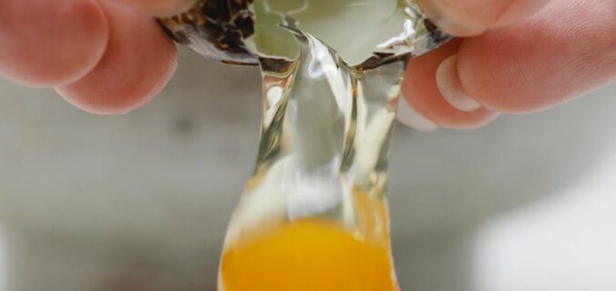 person breaking quail egg while preparing breakfast